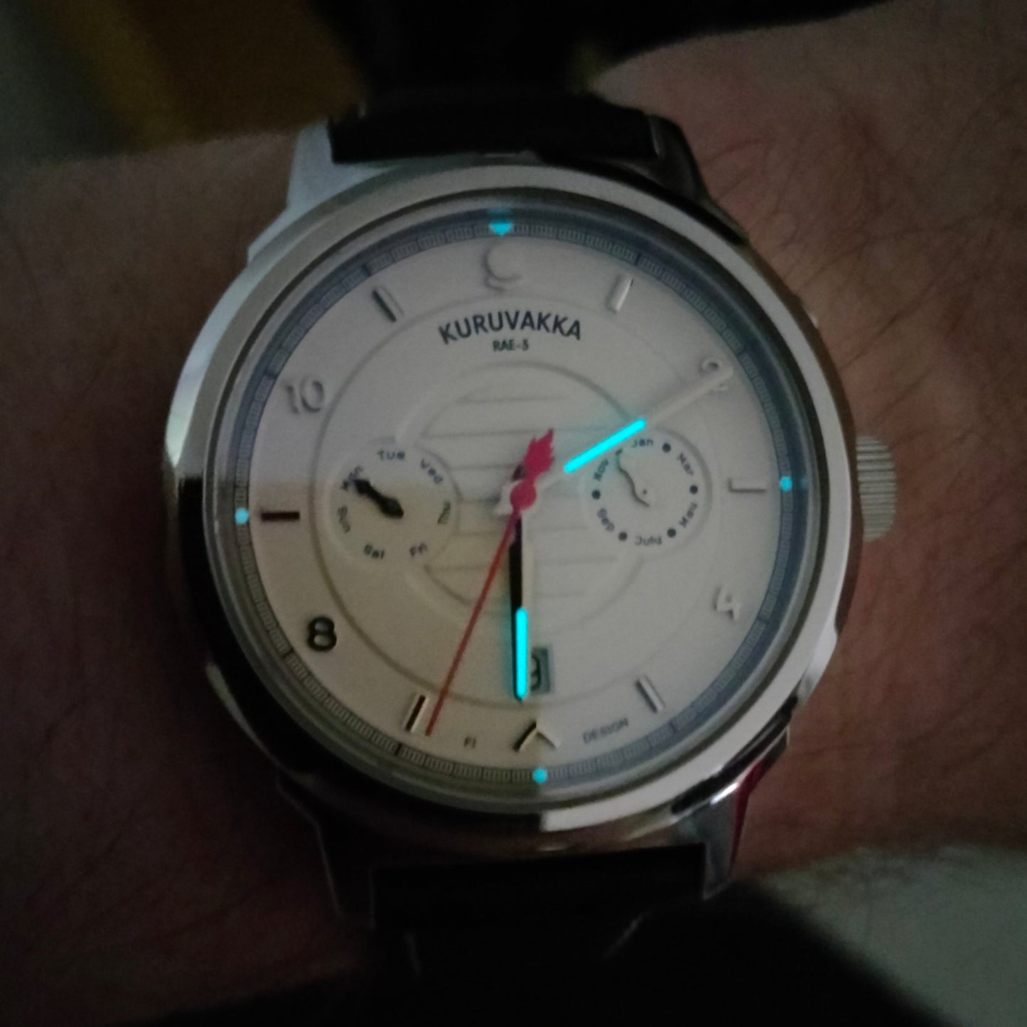 Presenting the lume of kuruvakka wristwatch. Watch is on a wrist in low light showing the front side and the lume on hands and indexes.