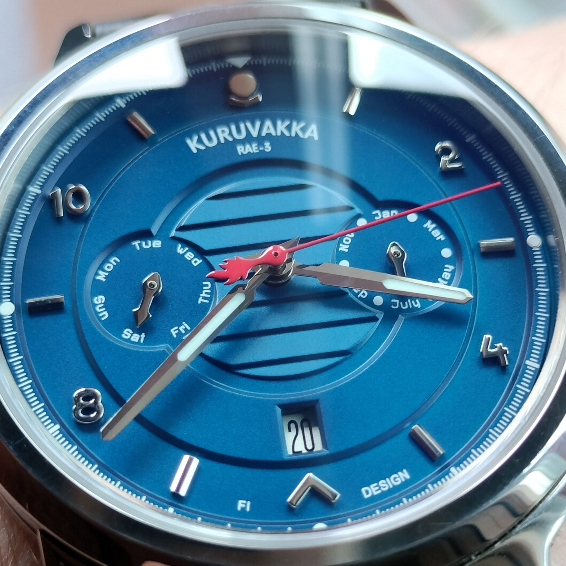 Close up of a premium mechanical wristwatch with blue dial and day, weekday, month functions. Front faced and case in an angle.